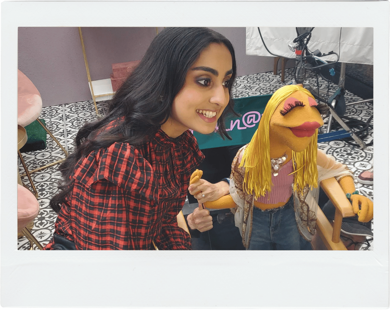 A young girl smiles as she poses with a blond haired puppet 