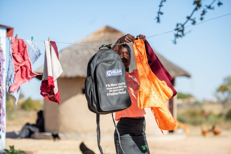 Photograph captures young woman in Zimbabwe hanging items on a clothesline.