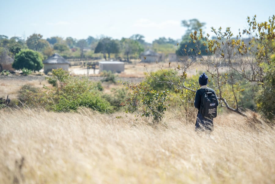 Young woman walks through high grass in Zimbabwe.
